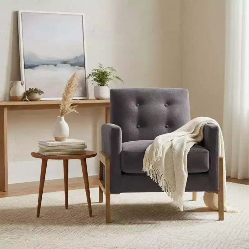 Poltrona moderna ed elegante con schienale trapuntato, rivestita in tessuto e con struttura in legno massello, ideale per il relax e la lettura in salotto
