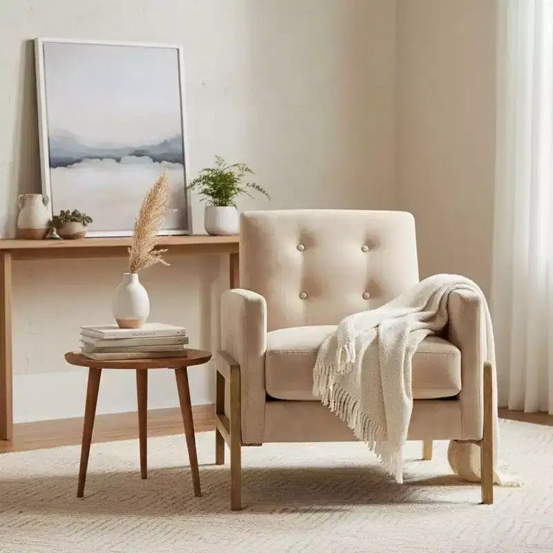 Poltrona moderna ed elegante con schienale trapuntato, rivestita in tessuto e con struttura in legno massello, ideale per il relax e la lettura in salotto